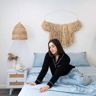 lady sitting in sheets admiring the soft texture of the bamboo ocean blue fabric sheets