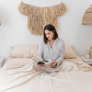 lady sitting in sand dunes bamboo sheets reading a magazine