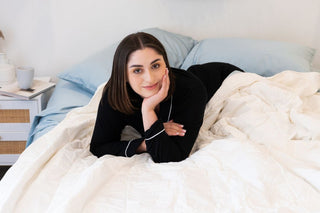 women lying on bed smiling on top of a white quilt