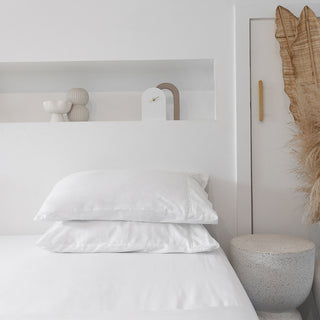 white room with two white pillows on a white sheet on bed