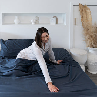 lady in bed feeling charcoal sheets with hand while smiling