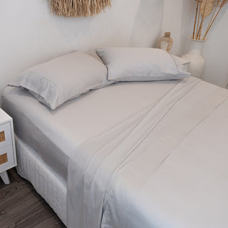 silver bamboo sheets on bed with pillowcases with white and wooden interior pieces in bedroom
