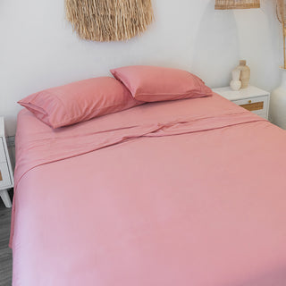 pink sunset blush bamboo sheets with pillowcases on bed in white room with white wooden interior accessories