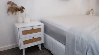 white bedroom with white wooden sideboard with silver bamboo sheets