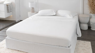 white bedroom wooden floor with white sheets with pillowcases on mattress