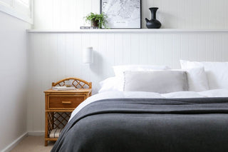 white room with a charcoal woolen blanket open on end of bed