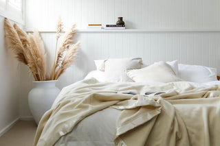 white room with white board walls with a ivory woolen blanket open on a bed
