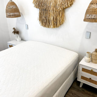 a white bamboo mattress protector on a mattress in a white room