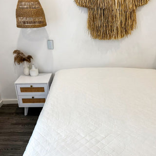 a white bamboo mattress protector in a white room with a white and wooden side dresser