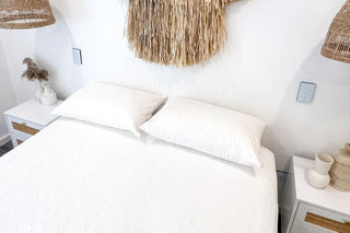 white bamboo pillow protectors on a white bamboo mattress protector on a mattress in a white room with white and wooden furnishings