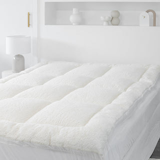  A close up of a bed with a Sienna Living Snuggle mattress topper in white bedroom